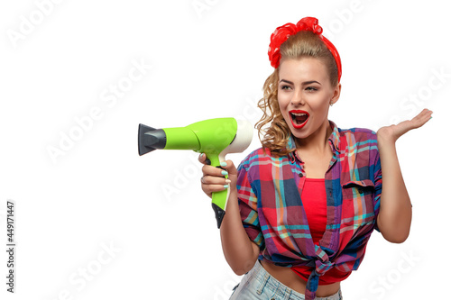 Half body portrait of young woman in pinup clothes with hairdryer makes attations photo