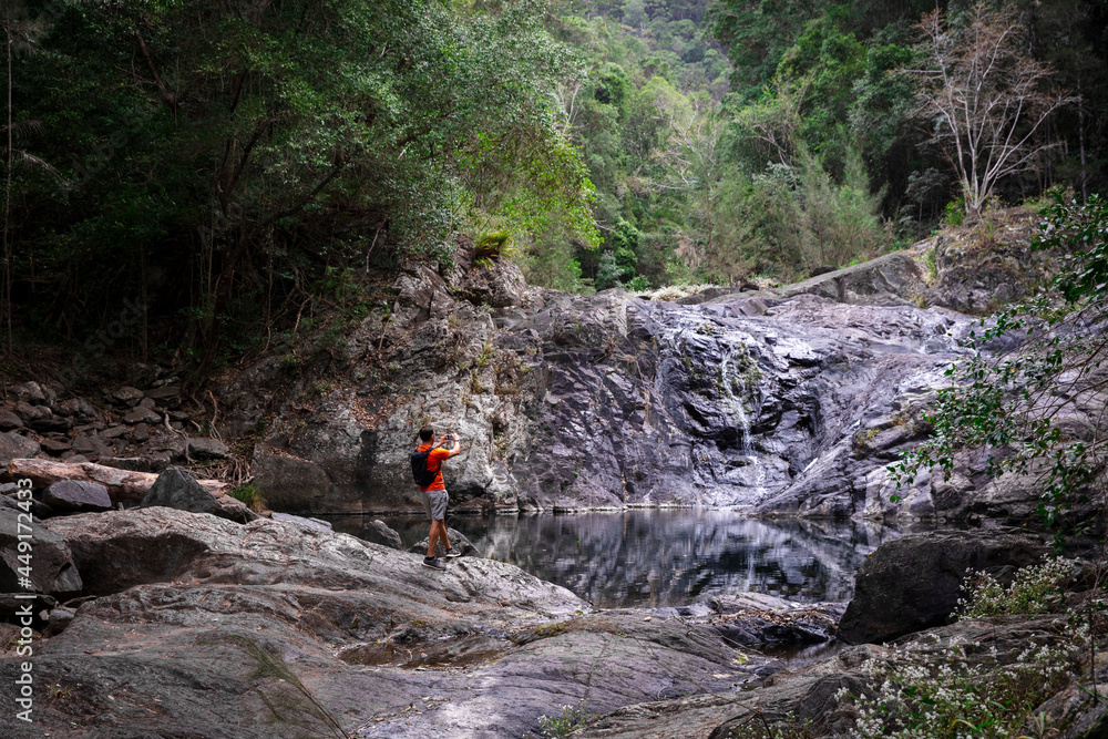 Bushwalker at rocky rainforest waterfall Bushwalker at rocky rainforest waterfall