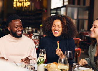 Woman eating meal and laughing in restaurant