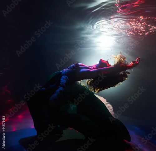 a woman dances underwater in a magical light