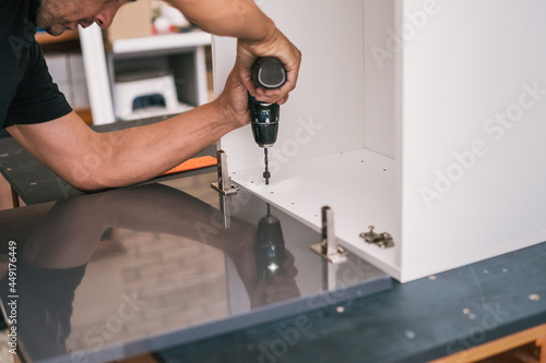 Wallpaper Mural Adult man drilling a wooden surface of a furniture for kitchen Torontodigital.ca