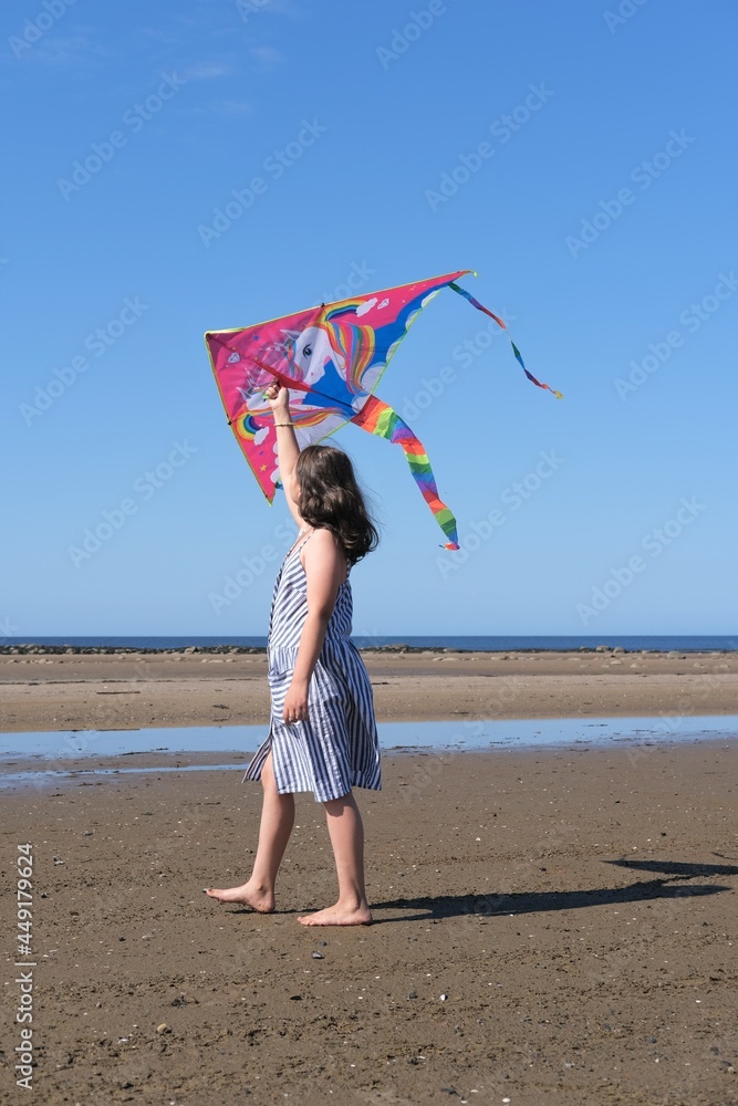 The girl plays with a kite on the sea.