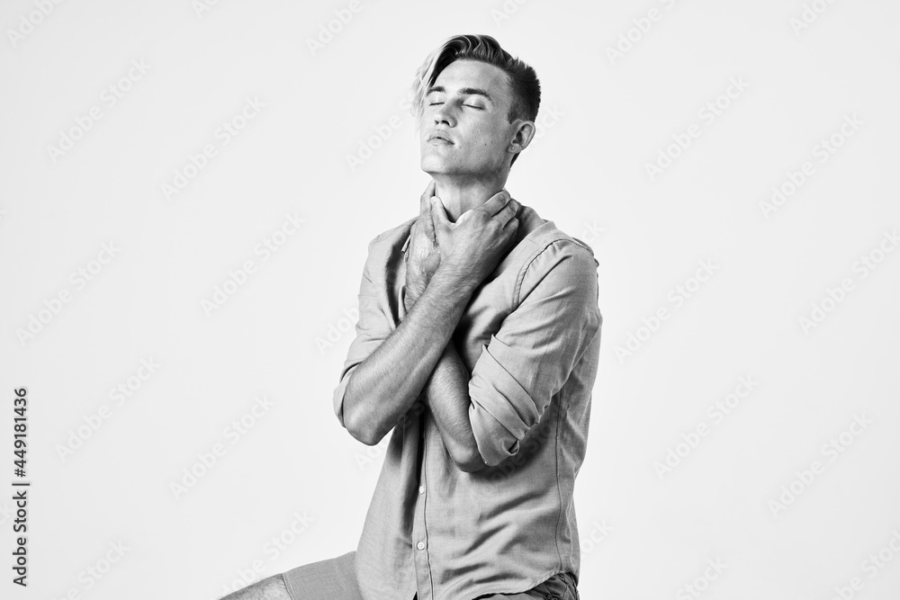 a handsome man with a fashionable hairstyle holds his hands behind his head light background posing a handsome man with a fashionable hairstyle holds his hands behind his head light background posing