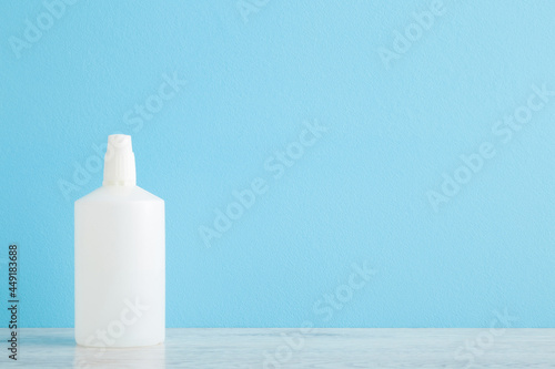 New white bottle of hydrogen peroxide on table at light blue wall background. Pastel color. Closeup. Front view. Product for skin wound cleaning. Empty place for text or logo. photo