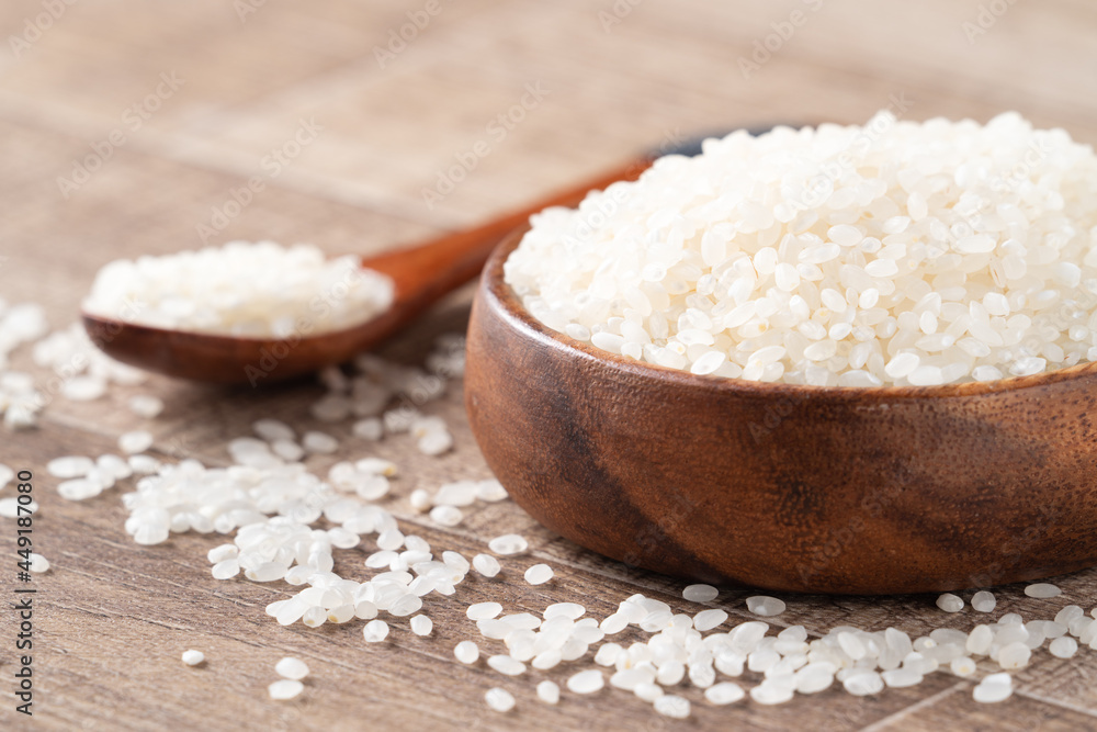 Raw white rice in a wooden bowl over table. Raw white rice in a wooden bowl over table.