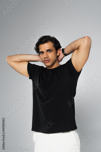young stylish man in black t-shirt posing isolated on grey