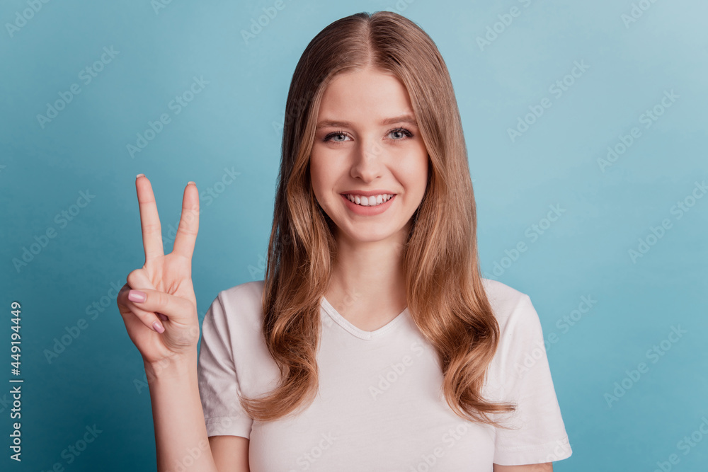 Portrait of friendly positive charming lady show v-sign peace gesture on blue background Portrait of friendly positive charming lady show v-sign peace gesture on blue background