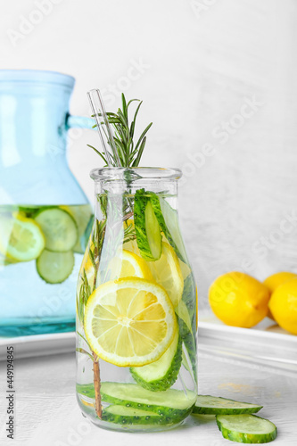 Bottle with cucumber lemonade on light background
