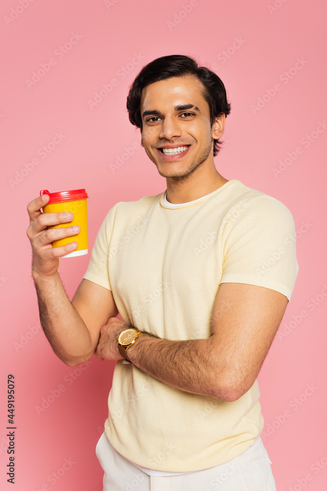 cheerful young man holding paper cup with coffee to go isolated on pink cheerful young man holding paper cup with coffee to go isolated on pink