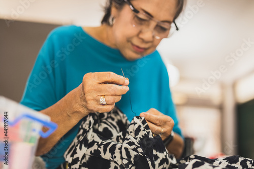 Εκτύπωση καμβά Elderly woman hands using needle and thread to mend a dress.