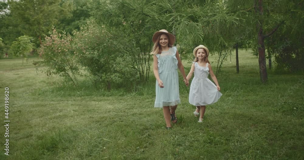 beautiful sisters walk around the park smiling the children hold hands beautiful sisters walk around the park smiling the children hold hands