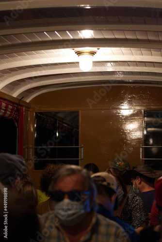 Tourists in wooden wagon of Brienz Rothorn Bahn in a tunnel with electric lights on. Photo taken July 21st, 2021, Flühli, Switzerland. 