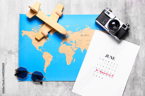 Calendar, world map, photo camera, sunglasses and wooden toy on grunge background