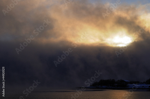 Large clouds in the sky above the water. Cold northern nature, the city of Murmansk. Cold autumn morning, the sun shines through the white clouds. Cold northern nature, the city of Murmansk.