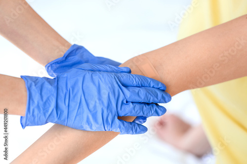 Nurse applying medical patch on young woman's arm in clinic, closeup