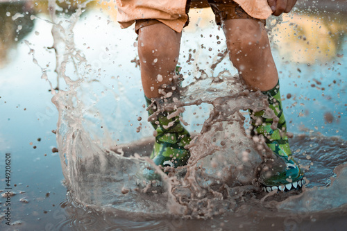 After the rain child is jumping into a puddle in green rubber boots. Drops fly up 