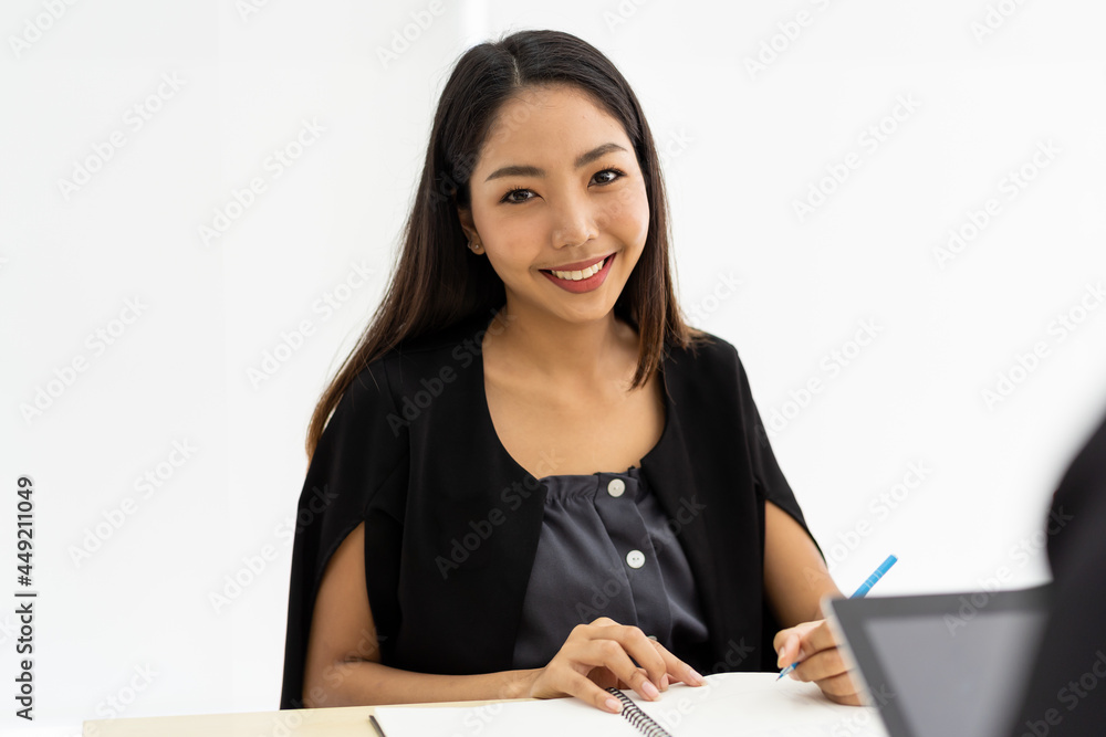 Smiling Asian business woman writing and working on office desk in the office Smiling Asian business woman writing and working on office desk in the office