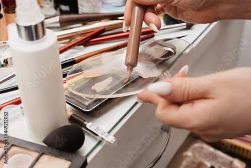 Shooting in a beauty salon. A picture of the hands of a makeup artist against the background of the workplace, with professional cosmetics and brushes laid out.