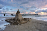 Zamek z piasku na plaży w Kołobrzegu, w pięknych barwach wschodzącego słońca.