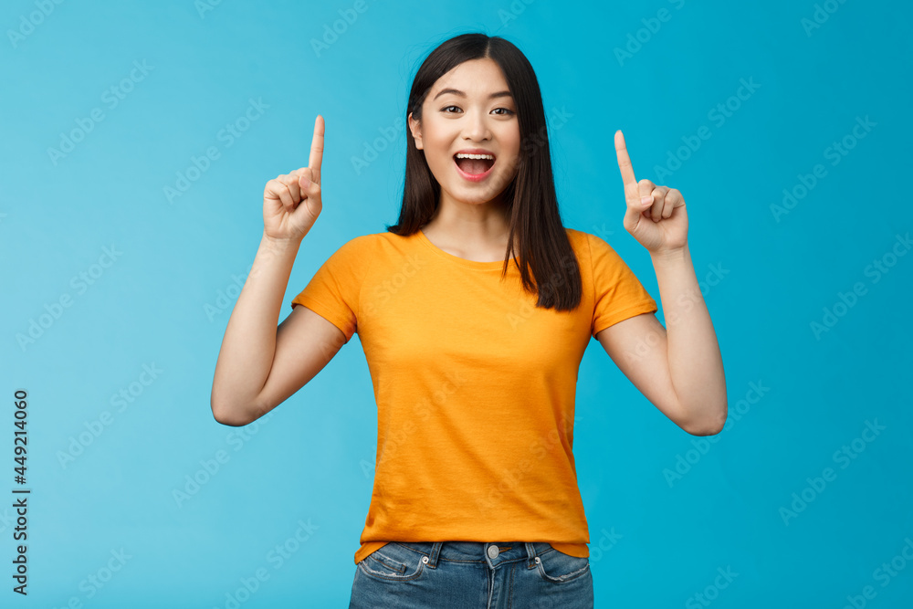 Amused asian girl introduce new product sharing promo with you raise Amused asian girl introduce new product sharing promo with you raise