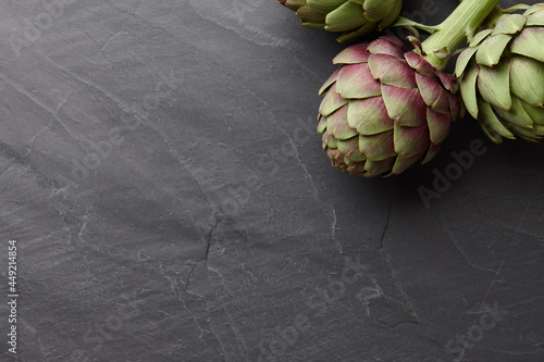 Foto Fresh artichokes on dark gray stone background