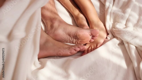 Couple in bed wakes up in the morning, male and female legs top view, white linen. photo