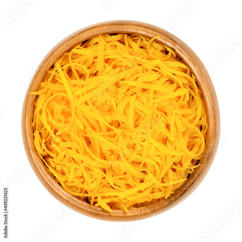 Fresh organic orange zest, orange peel strips, in a wooden bowl. Skin of ripe oranges, used for baking, or dried for tea blends. Close-up, from above, isolated on white background, macro food photo.