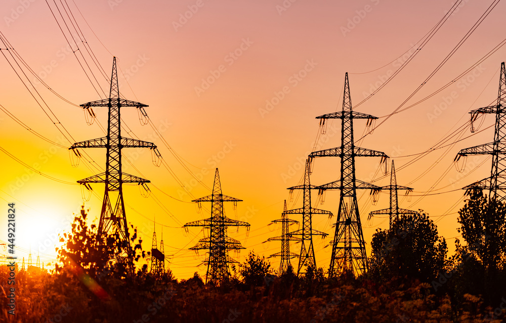 Silhouette of electric construction in orange sunlight. Electrical industrial distribution line.