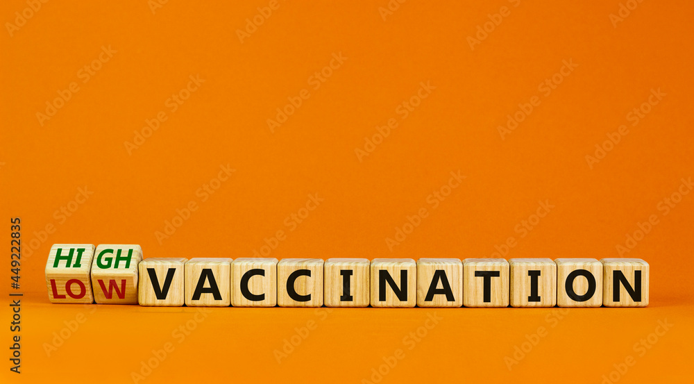High or low vaccination symbol. Turned wooden cubes and changed words 'low vaccination' to 'high vaccination'. Beautiful orange background, copy space. Medical, covid-19 pandemic vaccination concept. High or low vaccination symbol. Turned wooden cubes and changed words 'low vaccination' to 'high vaccination'. Beautiful orange background, copy space. Medical, covid-19 pandemic vaccination concept.