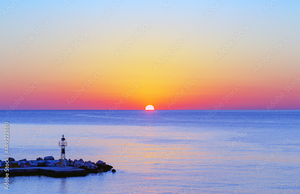Sunrise over the sea, view of the pier and lighthouse, horizontal view.
