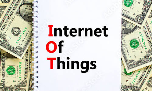 IOT, internet of things symbol. Words 'IOT, internet of things' on white note. Beautiful background from dollar bills. Business, digital, IOT, internet of things concept.