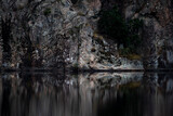 Rock face reflecting in the water of a calm forest lake.. Shot in Sweden, Scandinavia