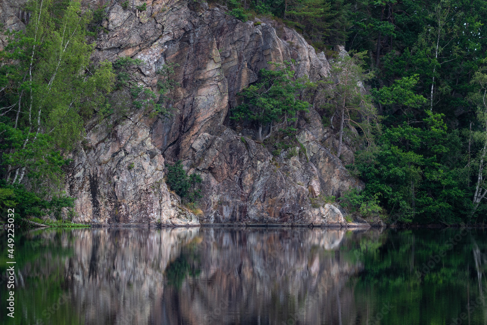 Hillside and trees reflecting in the water of a calm forest lake.. Shot in Sweden, Scandinavia Hillside and trees reflecting in the water of a calm forest lake.. Shot in Sweden, Scandinavia