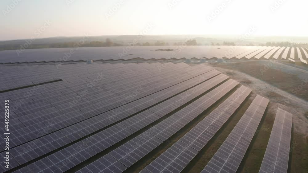 Aerial sunrise view of solar panels on a field powering factory. Field of solar panels that drives steel factory for stustainability Aerial sunrise view of solar panels on a field powering factory. Field of solar panels that drives steel factory for stustainability