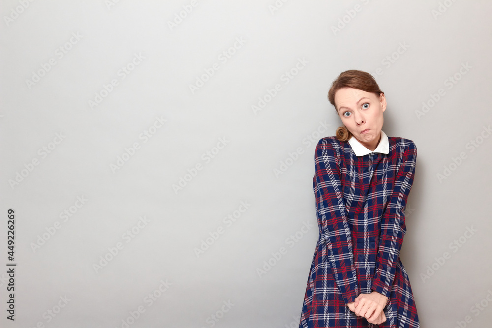 Portrait of funny confused young blond woman wearing checkered dress Portrait of funny confused young blond woman wearing checkered dress