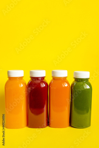 Fresh juices or smoothies of fruits and vegetables in bottles on a yellow background. The concept of a healthy diet, diet or detox