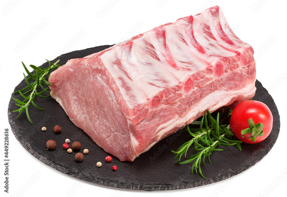 raw pork meat with rosemar, tomato and peppercorn on black round stone plate isolated on white background. Clipping path and full depth of field