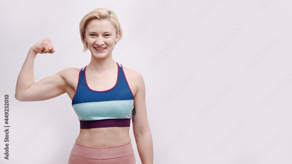 Girl dressed in activewear showing her biceps. Strong girl posing for the camera showing her muscles and strength. Concept of fitness and gym. Isolated over white background studio. Girl dressed in activewear showing her biceps. Strong girl posing for the camera showing her muscles and strength. Concept of fitness and gym. Isolated over white background studio.