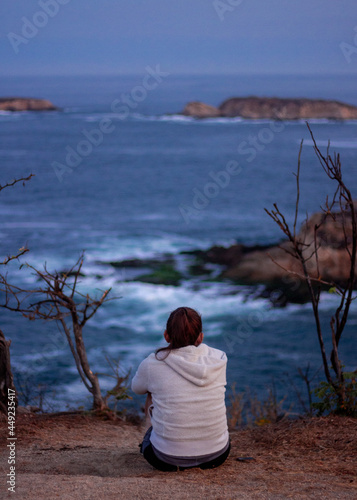 Mujer sentada mirando el mar a lo lejos