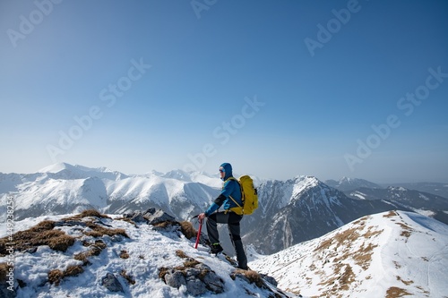 A strong, determined and active climber's success with a yellow backpack. He gets peaks in winter.