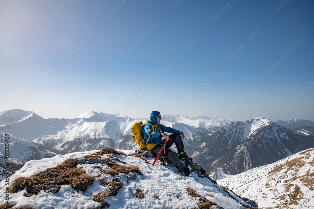 Hiker with yellow backpack at the top of a mountain. Beautifull winter landscape.