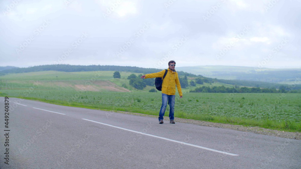 man hitchhiking in the countryside, on an empty road without cars