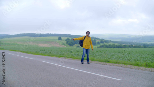 man hitchhiking in the countryside  on an empty road without cars