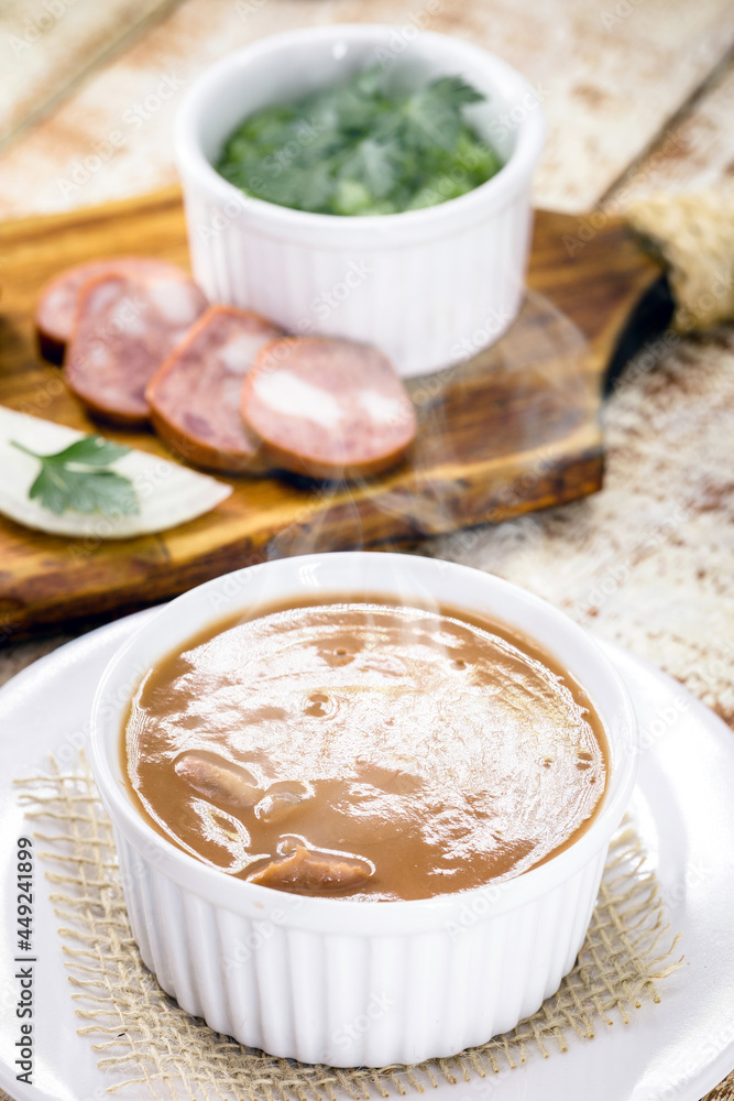 Brazilian bean broth, homemade bean soup served warm in winter, with ingredients in the background Brazilian bean broth, homemade bean soup served warm in winter, with ingredients in the background