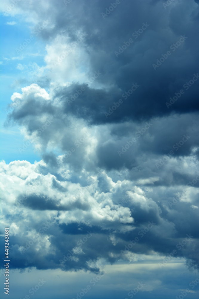 Obraz premium Large dark clouds before the start of rain and thunderstorms, with part of the blue sky