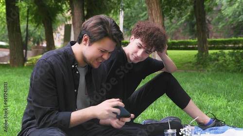 The guy plays the game on the phone, and the second watches the process in nature in the summer