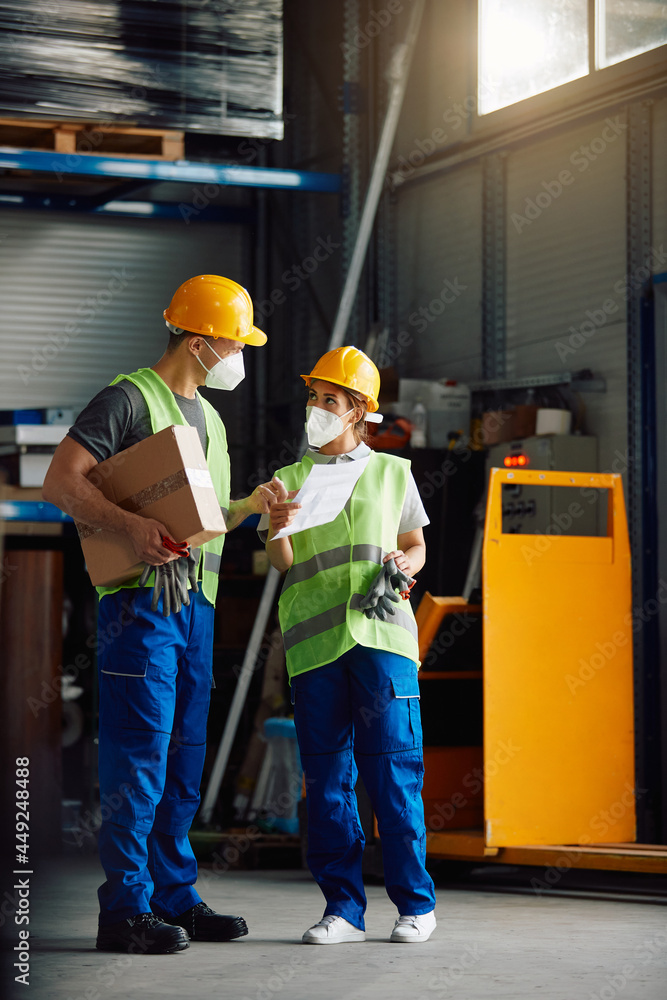 Warehouse workers with protective face masks analyse shipment list at storage compartment. Warehouse workers with protective face masks analyse shipment list at storage compartment.