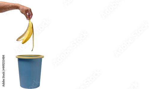 Fotografija In a man hand, banana peel is thrown into trash.Food waste.