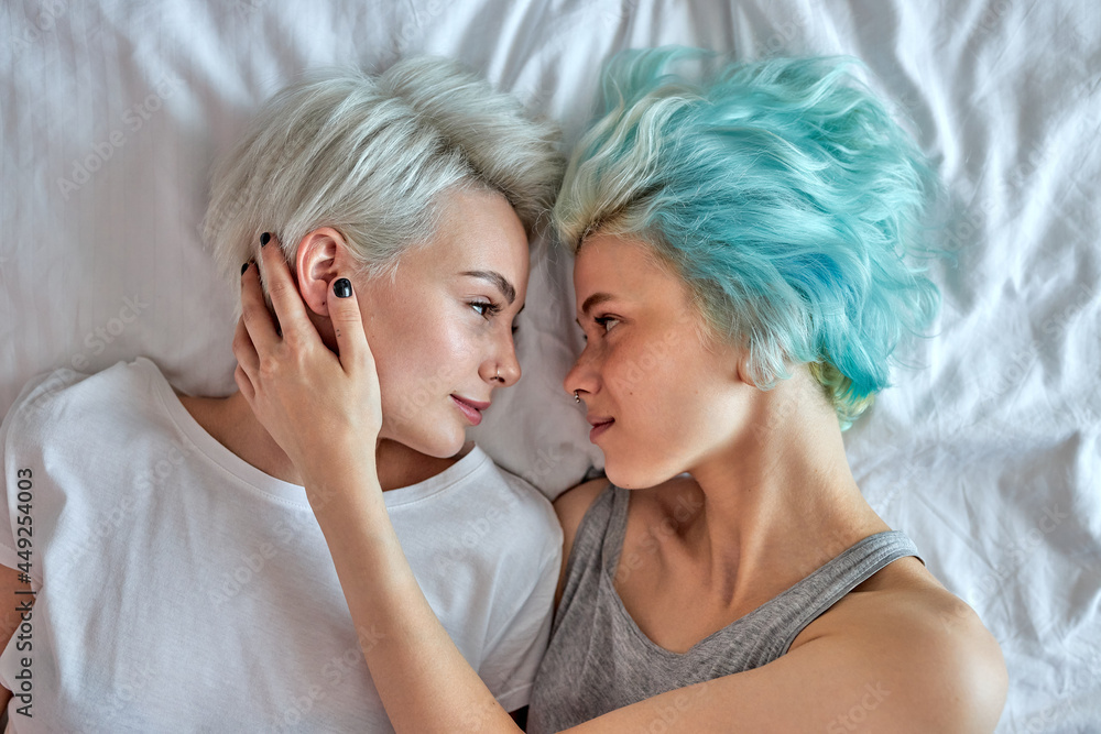 Love and desire. Young lgbt couple in love. Loving couple of lesbian lovers lying on bed at weekends. Sexy women in romantic relationship. Lesbian partnership. Freedom and equality. Top view.
