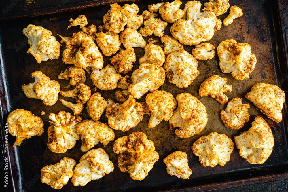 Raw Cauliflower Florets Tossed in a Curry Spice Mixture: Raw cauliflower florets covered in spices on a sheet pan Raw Cauliflower Florets Tossed in a Curry Spice Mixture: Raw cauliflower florets covered in spices on a sheet pan